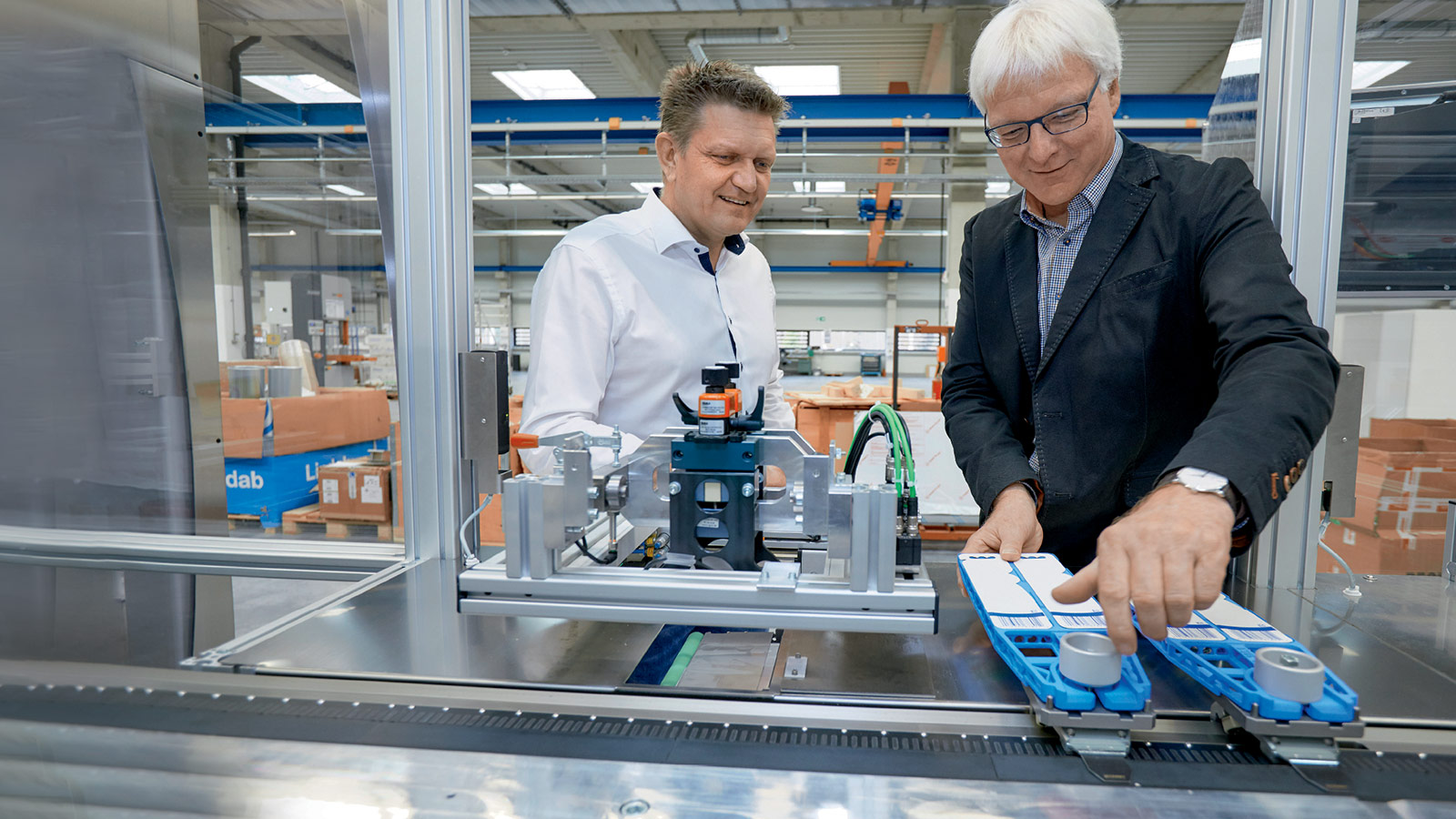 Jürgen Welker (right) of Koch Pac-Systeme shows Frank Würthner of Beckhoff how easy it is to switch out the blister carriers for rapid product changeovers.  