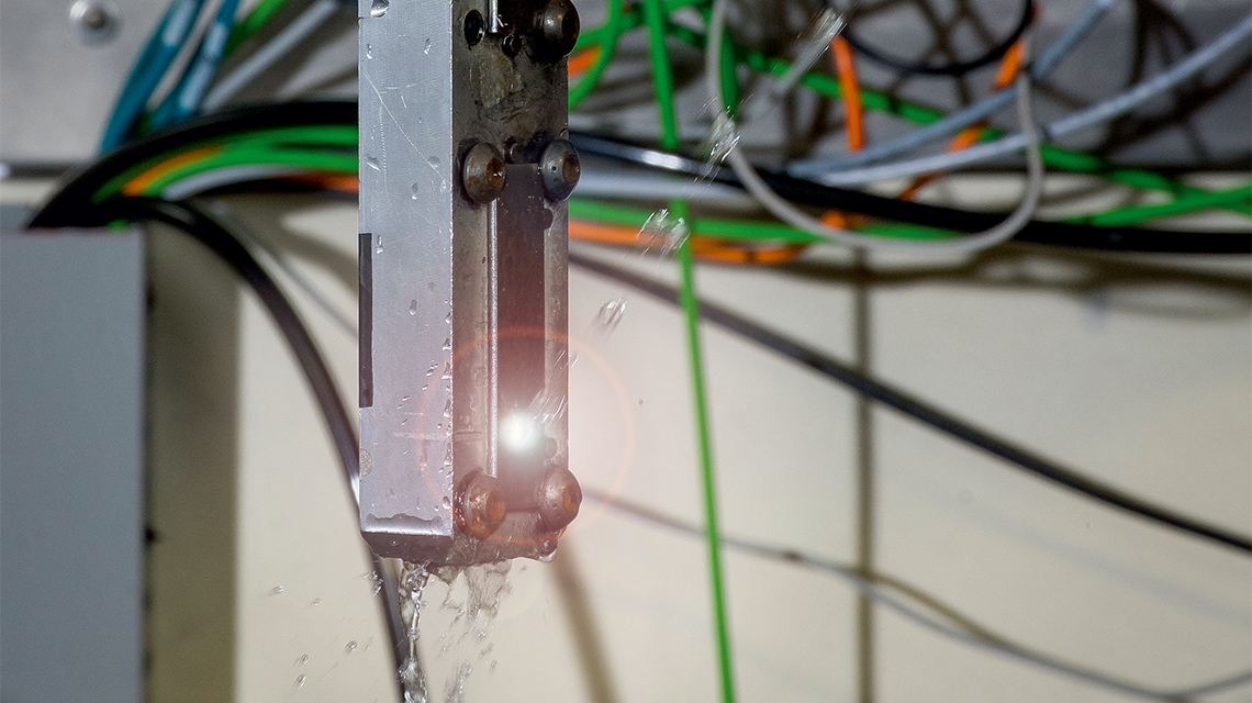 Laser Peening erhöht die Widerstandsfähigkeit von Metallteilen durch einen Prozess, bei dem ein Hochleistungslaserstrahl auf ein Werkstück gelenkt wird, während ein Wasserstrahl darüber fließt.  