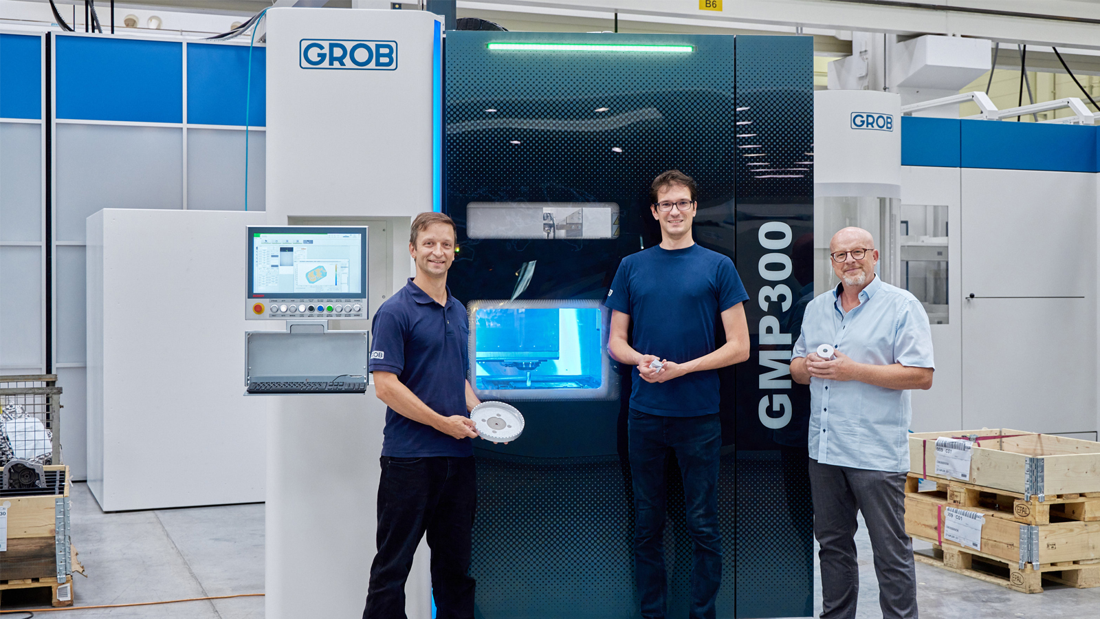 Emanuel Engelsberger and team leader Dr. Johannes Glasschröder, both from the additive manufacturing team at GROB-Werke, and Darius Wala, manager of the Beckhoff Munich branch, in front of the state-of-the-art and attractively designed GMP300 (from left to right).