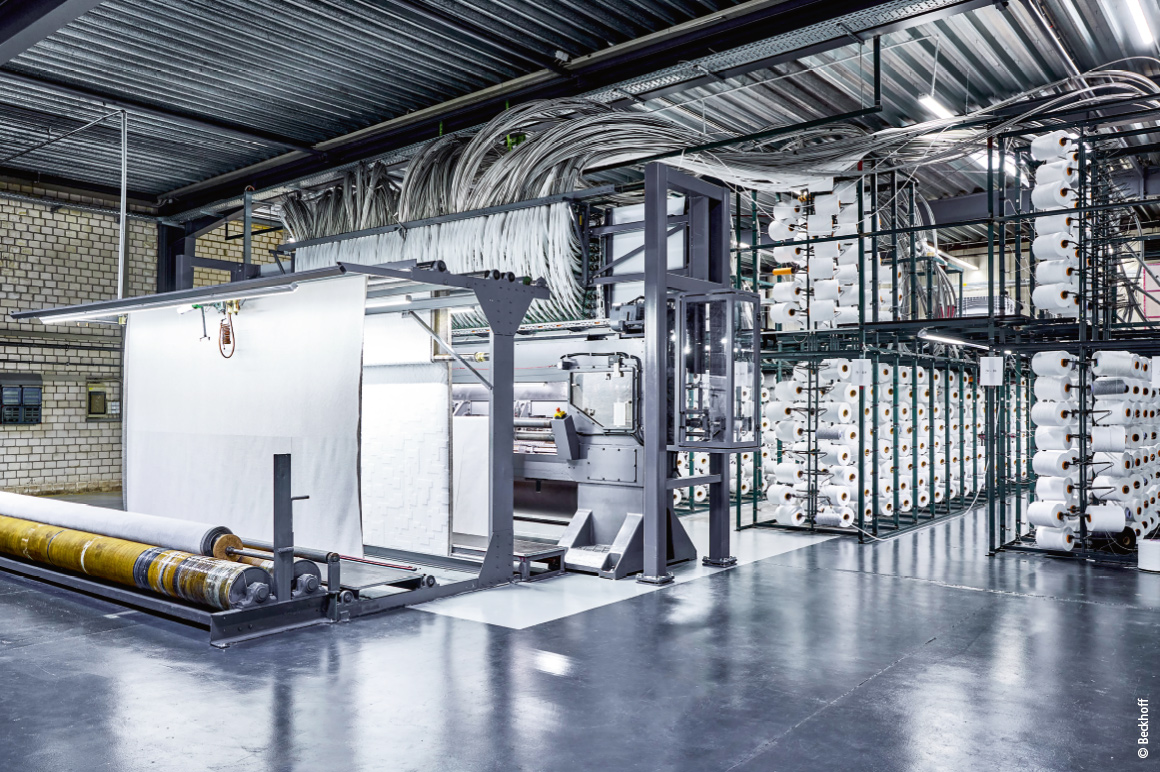 Beim Retrofit der Tuftingmaschine wurde die komplette Steuerungs- und Antriebstechnik ausgetauscht sowie die bisherige Garnspeisewalze durch 424 kompakte Schrittmotorantriebe ASI8114 mit integrierter Endstufe ersetzt.