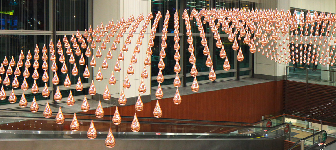 Mit „Kinetic Rain“ wurde am Changi Airport eine kinetische Skulptur, bestehend aus 1.216 hochglänzenden, verkupferten Aluminiumtropfen, realisiert. © Changi Airport Group Singapore
